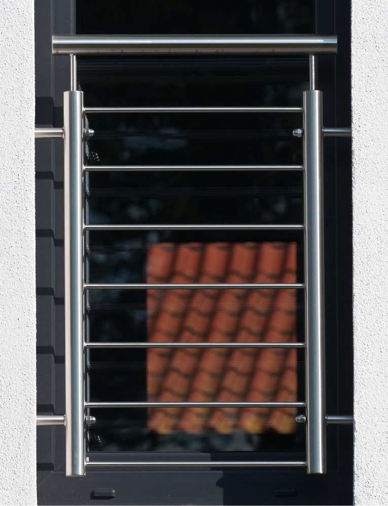 Fenstergitter_Referenz_3 Nahaufnahme eines Fenstergitters aus Edelstahl vor modernem Fenster.